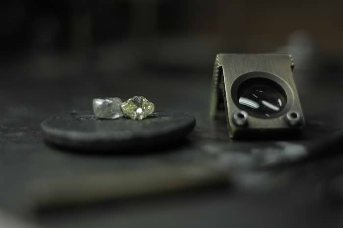 A rough diamond next to a polished diamond