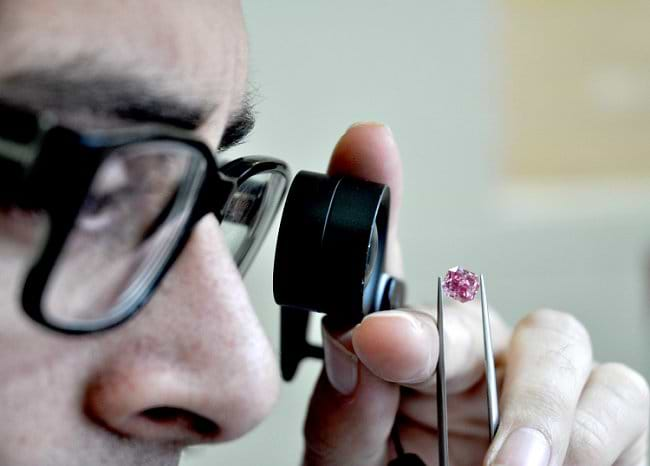 Shmulik Polnauer louping the 1.68-carat, Fancy Vivid Purplish Pink, Radiant-shaped diamond