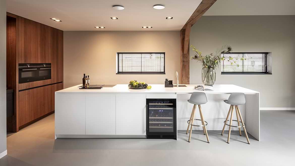 Luxe keuken, strakke keuken, minimalistisch design van B Dutch in Cuijk. Met solid surface Corian kookeiland, keukeneiland, en strakke houten keuken kastenwand.