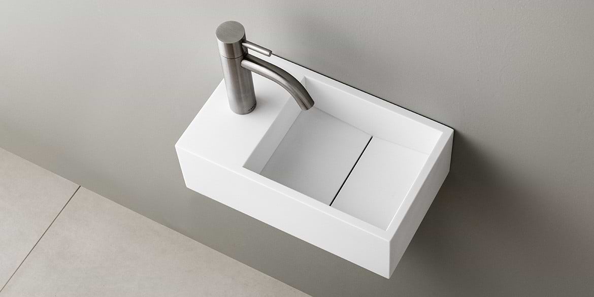 Solid Surface Corian toiletfontein, wasbak of wastafeltje voor op het toilet. Dit mat witte Corian toiltfonteintje kan met kraangat of zonder kraangat geleverd worden. De wasbak uitsparing zit rechts. Het Basics toiletfontein Rechts 300 heeft een lengte van 30 cm, diepte van 18 cm en hoogte van 10 cm.