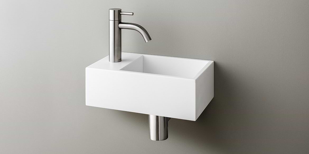 Solid Surface Corian toiletfontein, wasbak of wastafeltje voor op het toilet. Dit mat witte Corian toiltfonteintje kan met kraangat of zonder kraangat geleverd worden. De wasbak uitsparing zit rechts. Het Basics toiletfontein Rechts 300 heeft een lengte van 30 cm, diepte van 18 cm en hoogte van 10 cm.