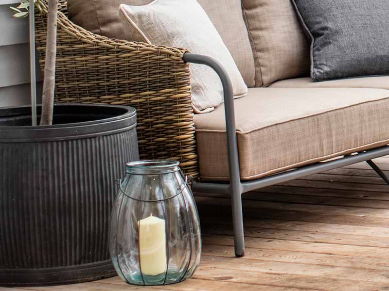 Detail crop of heyshott sofa with malmesbury planter and glass windlight in front