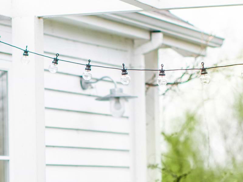 Festoon lights strung between frame of pegola