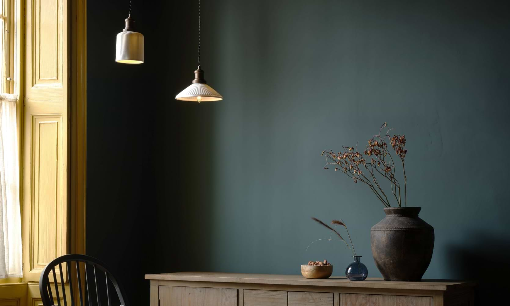 Beaulieu Ceramic Fluted Cone and Cylinder Pendants in lifestyle shot featuring shutters, sash window, a chair, sideboard, with bowls and vases.