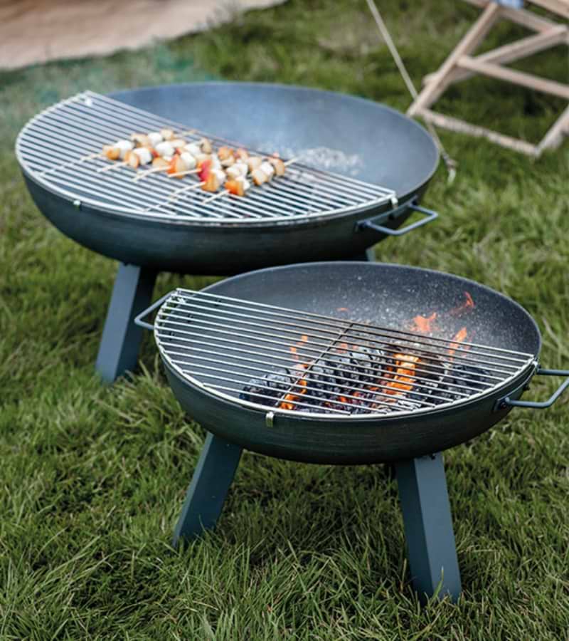 Stainless-steel Foscot 1/2 Grill clipped onto a fire pit, ideal for outdoor cooking.