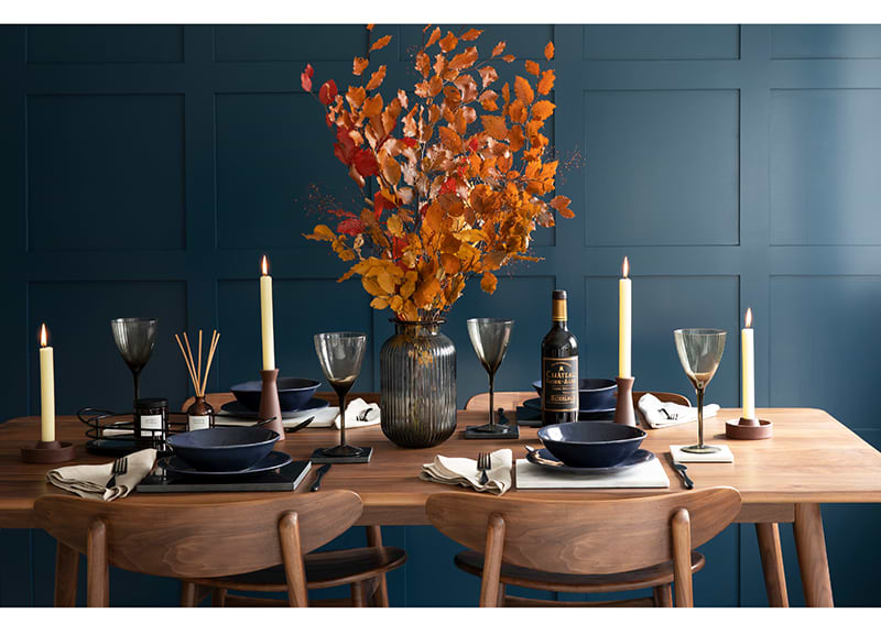 Table set with candles and wine with a blue wall behind