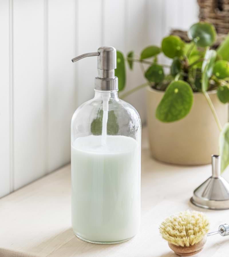 Refillable glass soap dispenser on a counter.