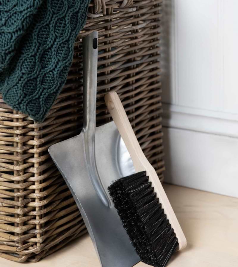 A household dustpan and brush leaning against a laundry basket.