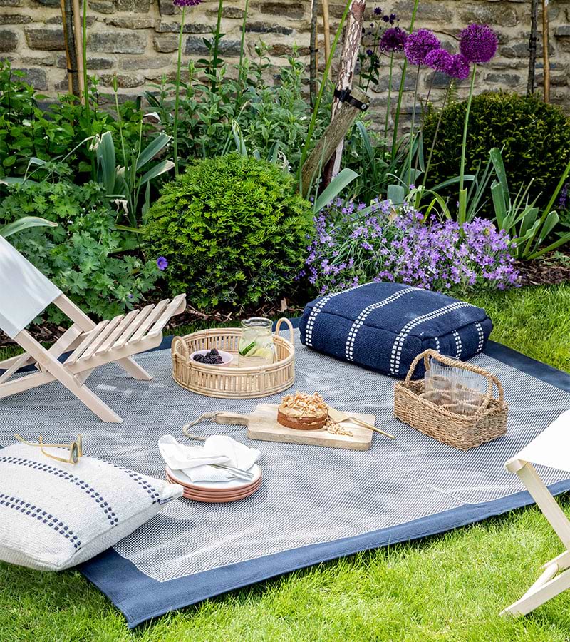 Blue picnic rug on grass with deck chair