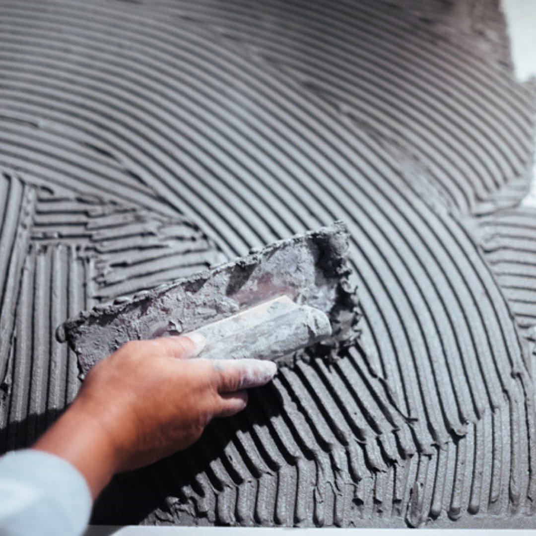 A hand applying grout to wall tile preperation