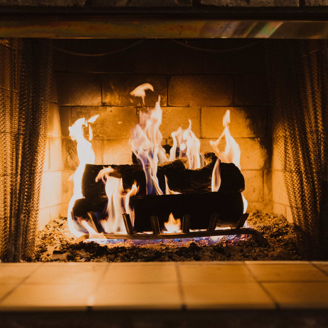 A warm, brightly lit fire in a fireplace using fire glow to highlight white tiles