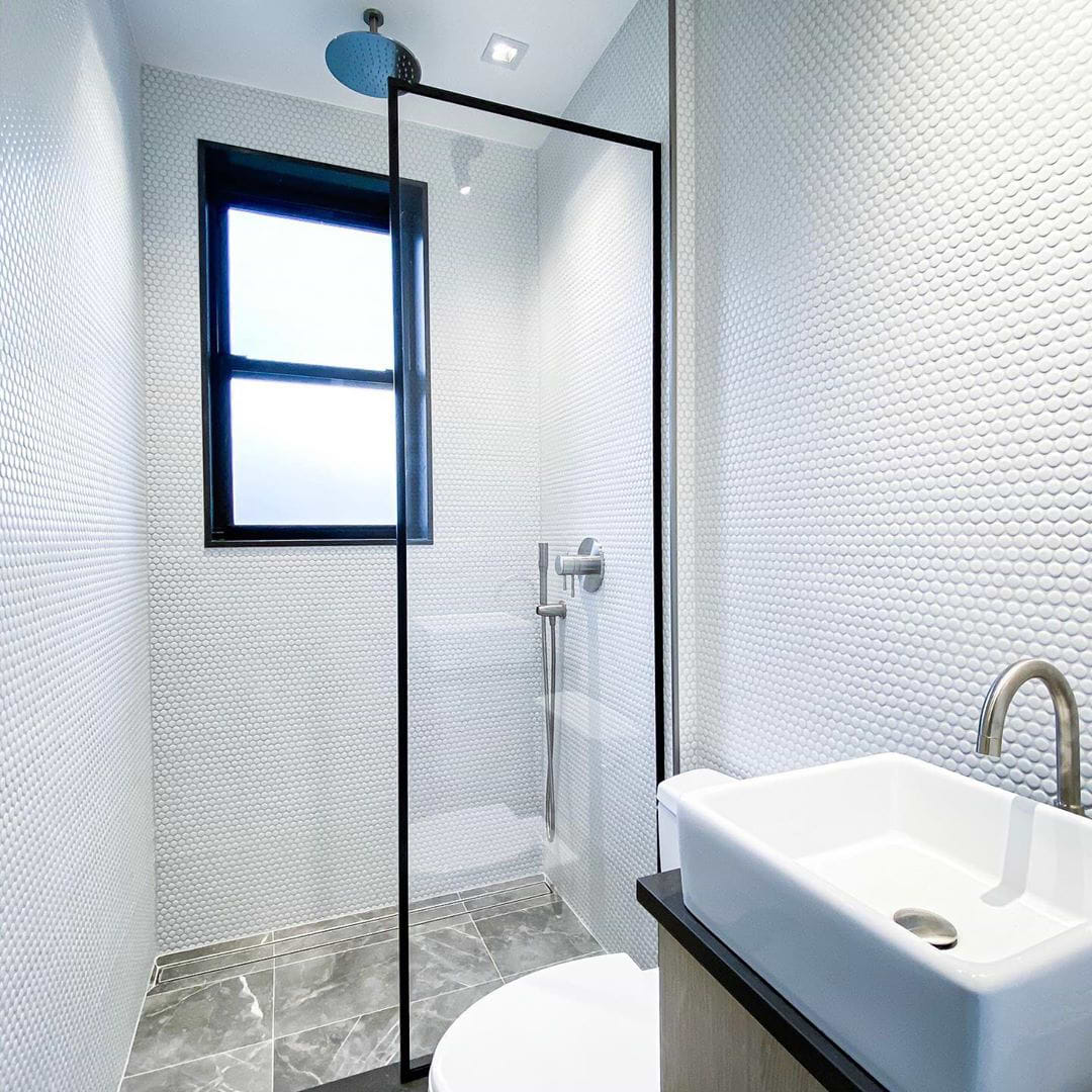 A modern white bathroom with walk in shower showing Paradise White Penny Round Tile on the wall