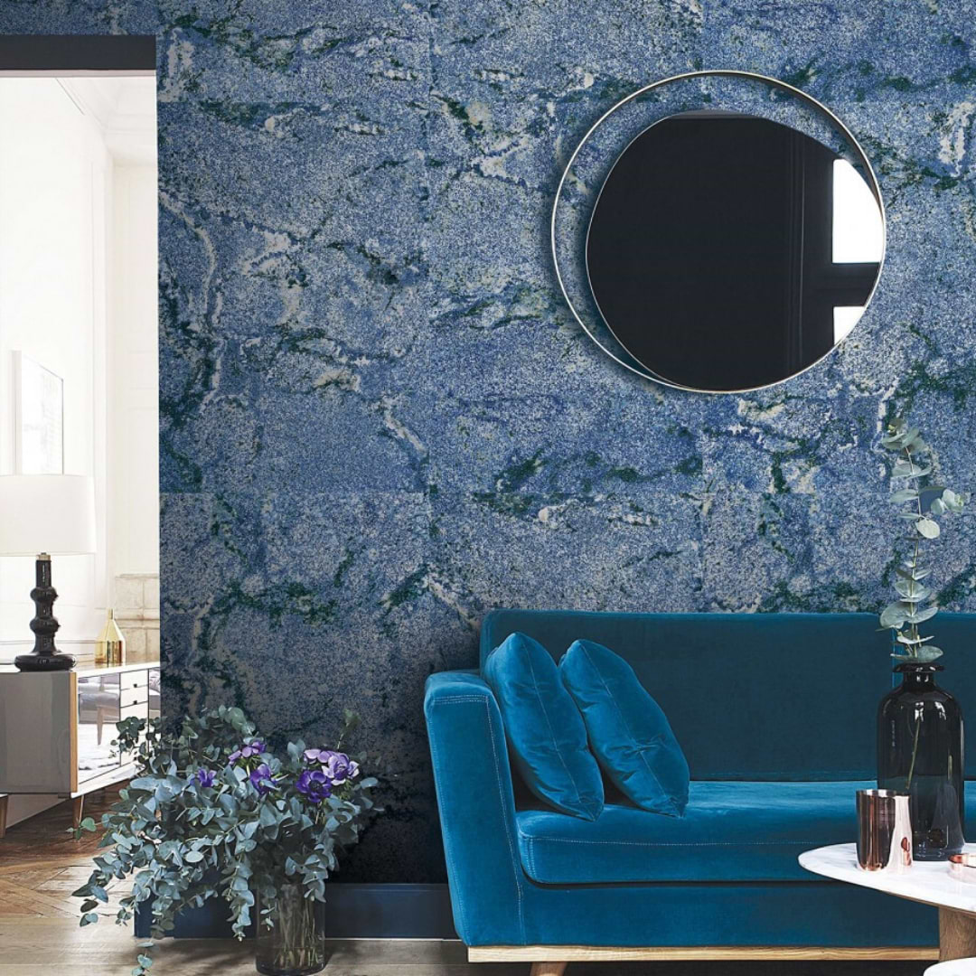 Beautiful stone look porcelain tile in a striking blue with dark veining against a living room wall.