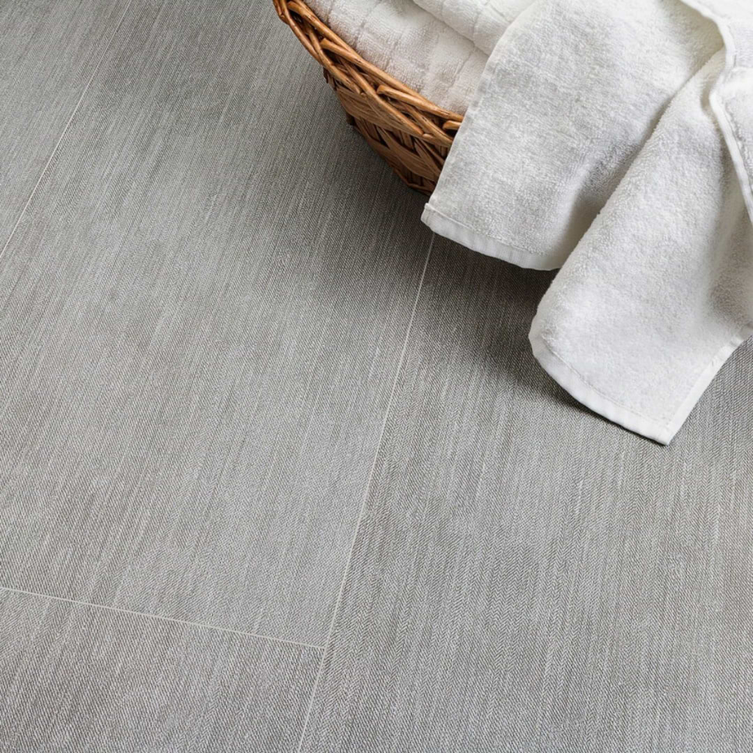 Stacy Garcia Gabardine Heather 12x32 Porcelain Tile shown on floor with towel basket on top