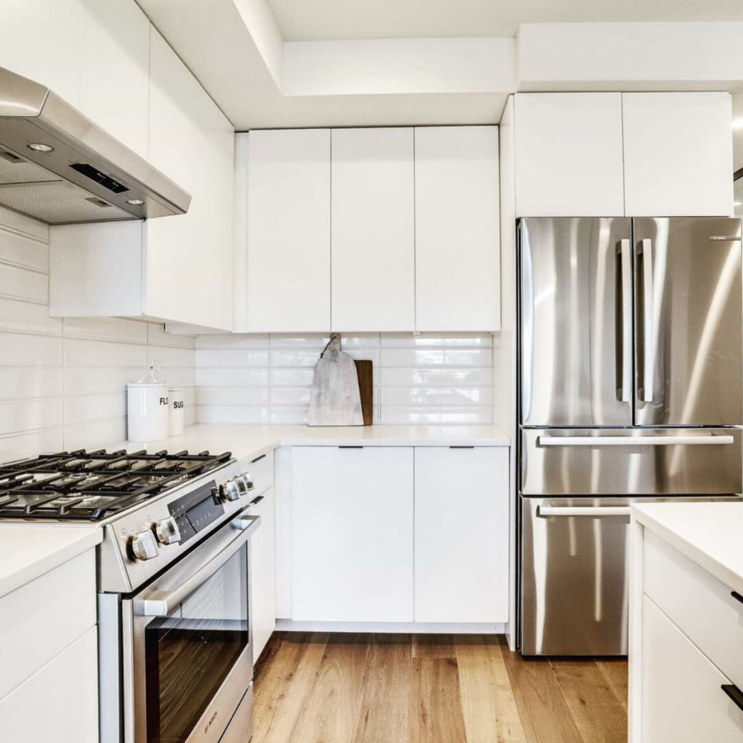 Norwalk Frame White 4x24 Polished Ceramic Wall Tile shown laid horizontally on the kitchen wall. It's also used for the stovetop backsplash.  