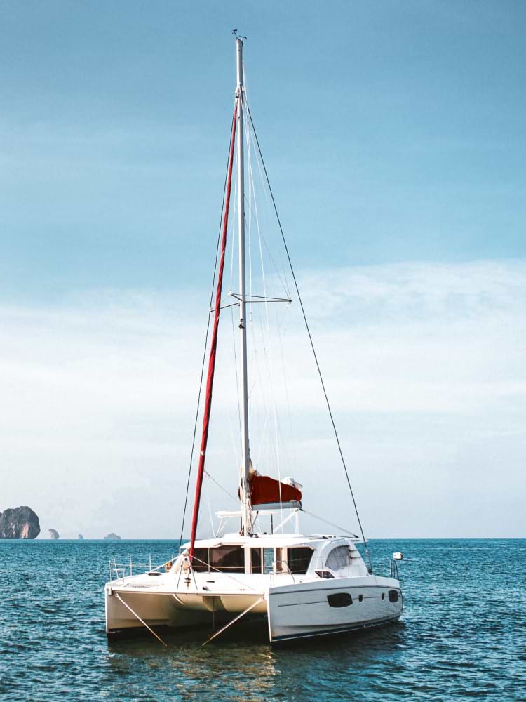Catamaran in body of water with background of cloudy sky