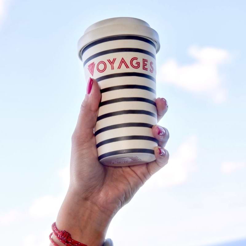 person holding striped virgin voyages cup in air