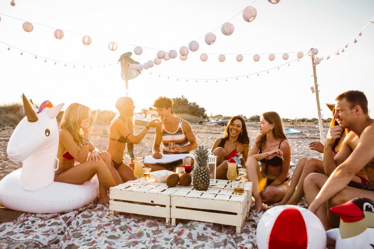 Group of people sitting around a beach table with drinks