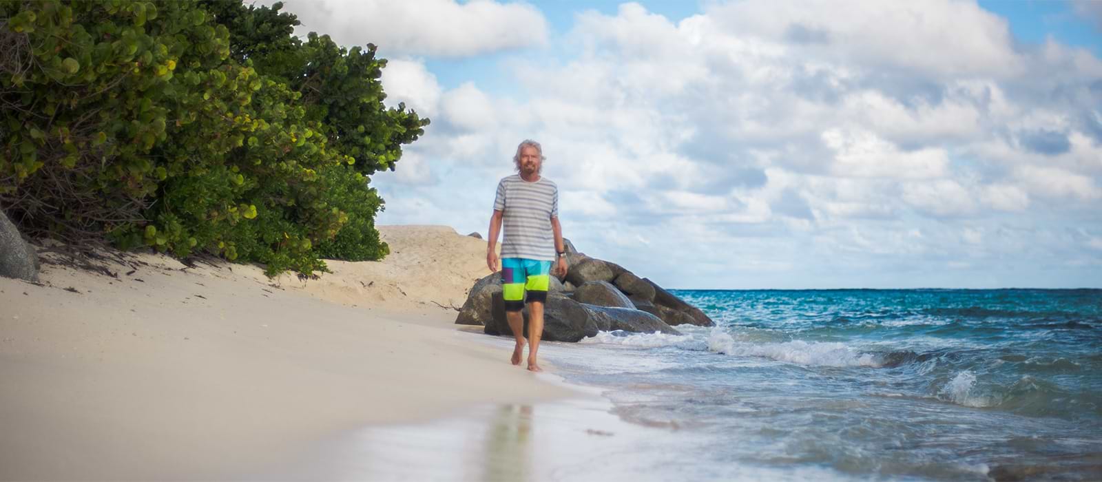 Richard Branson living the Virgin Voyages lifestyle on the beach.