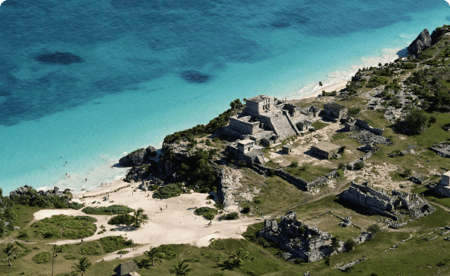 Birds-eye view of ancient ruins next to a pristine beach.