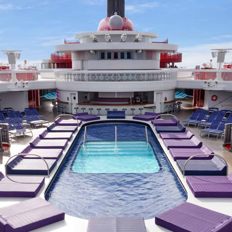 Virgin Voyages' Aquatic Club pool deck with purple sunbathing lounge chairs