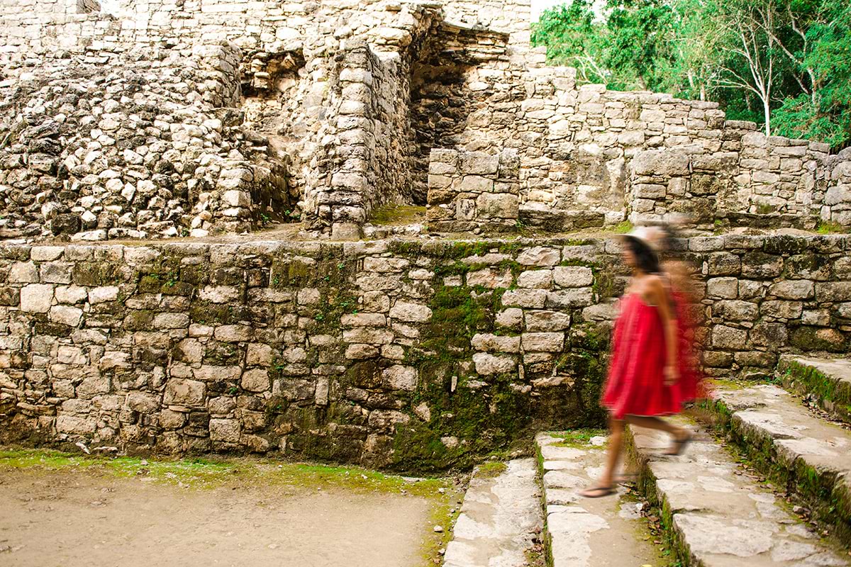 Blurry image of a lady wearing a red dress while walking downstairs at Mayan ruins place