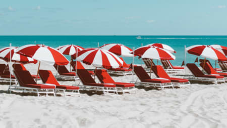 Red beach chairs with red and white umbrellas