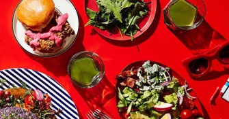 Burger plate and salad served at red table