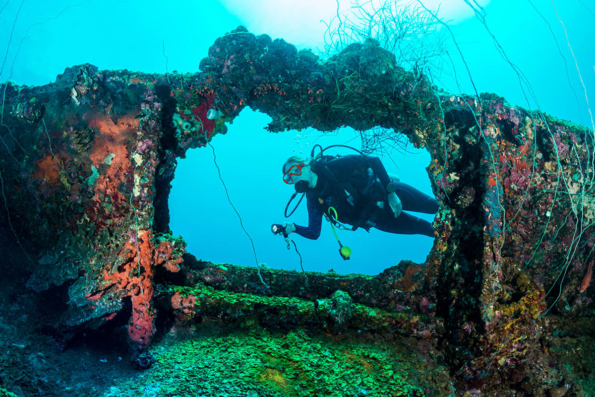 Scuba Diver exploring a shipwreck underwater.