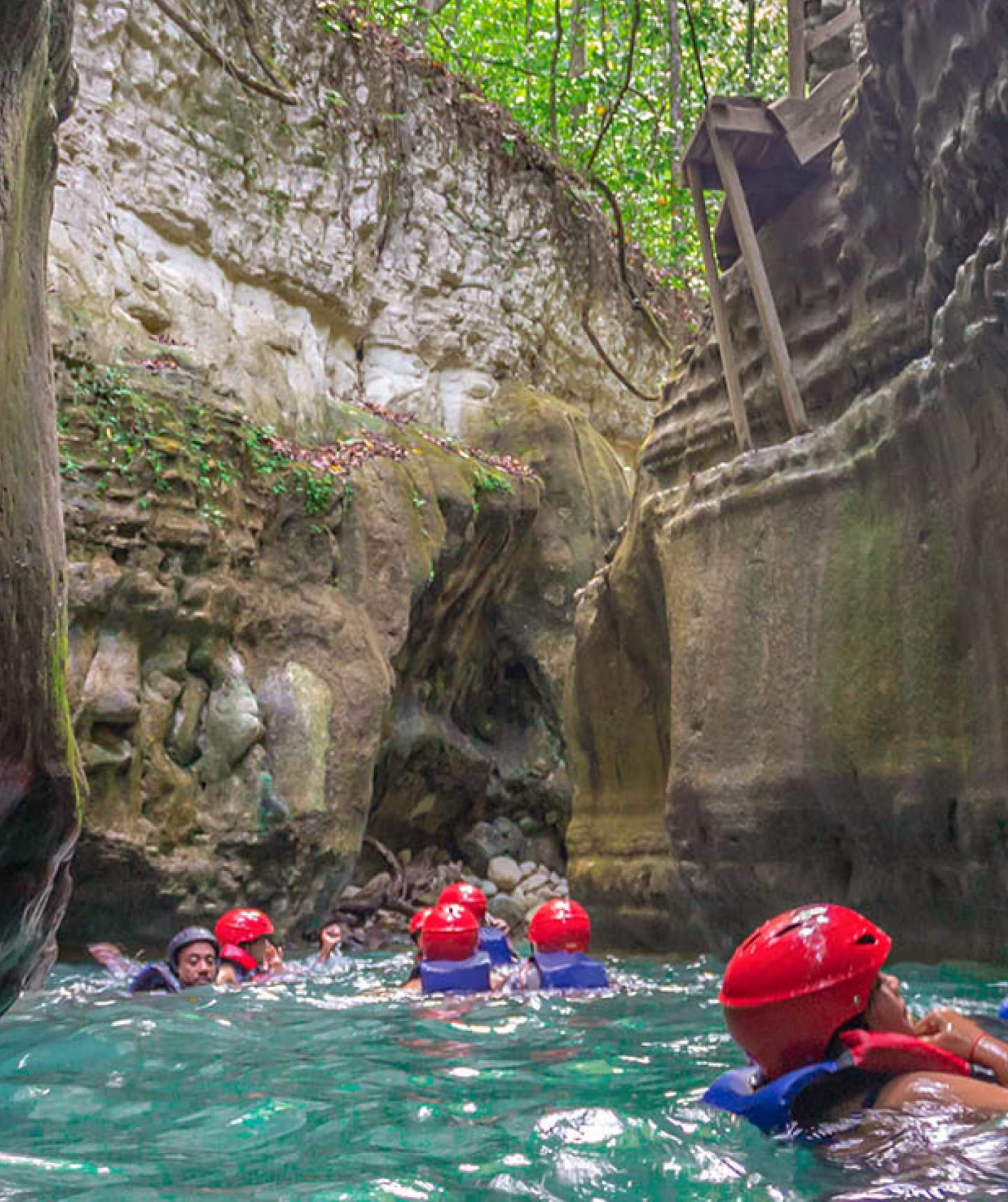 People swimming in river between high mountains