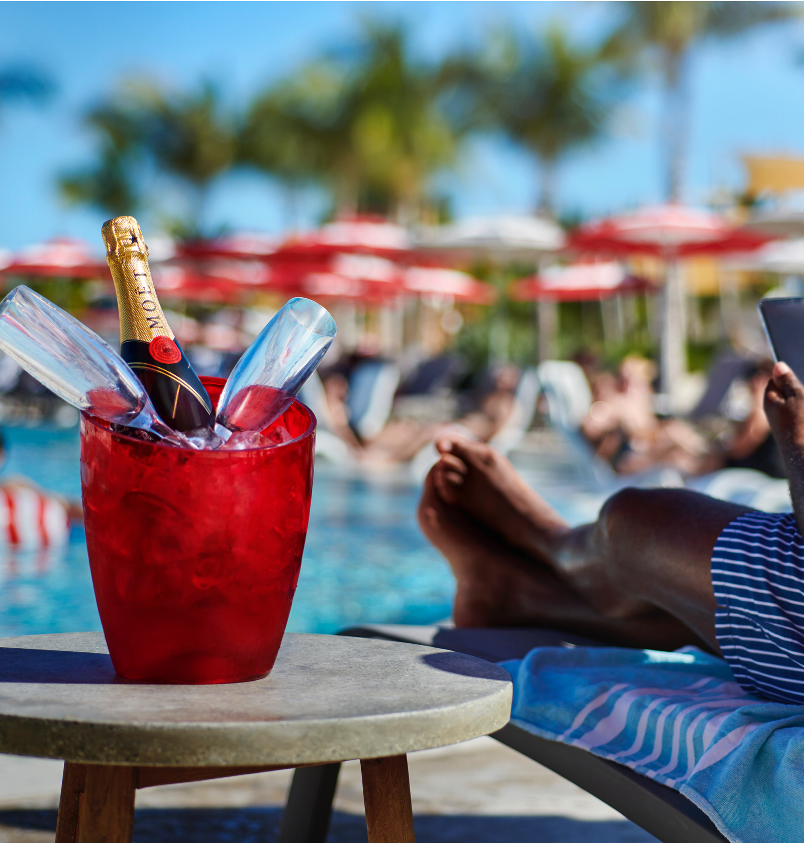 Bottle of Moet on Ice with two glasses next to the pool