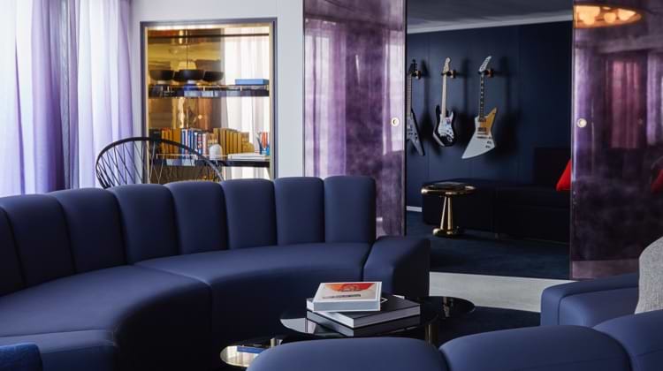 Virgin Voyages' interior view of Mega Rockstar Massive Suite living room with electric guitars hanging on the wall
