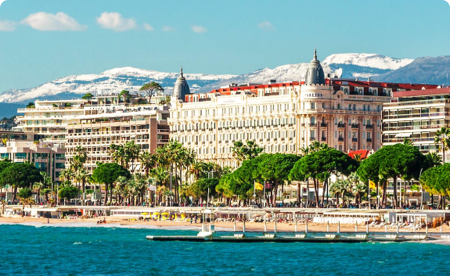 Tony buildings lining a blue shore in Cannes.