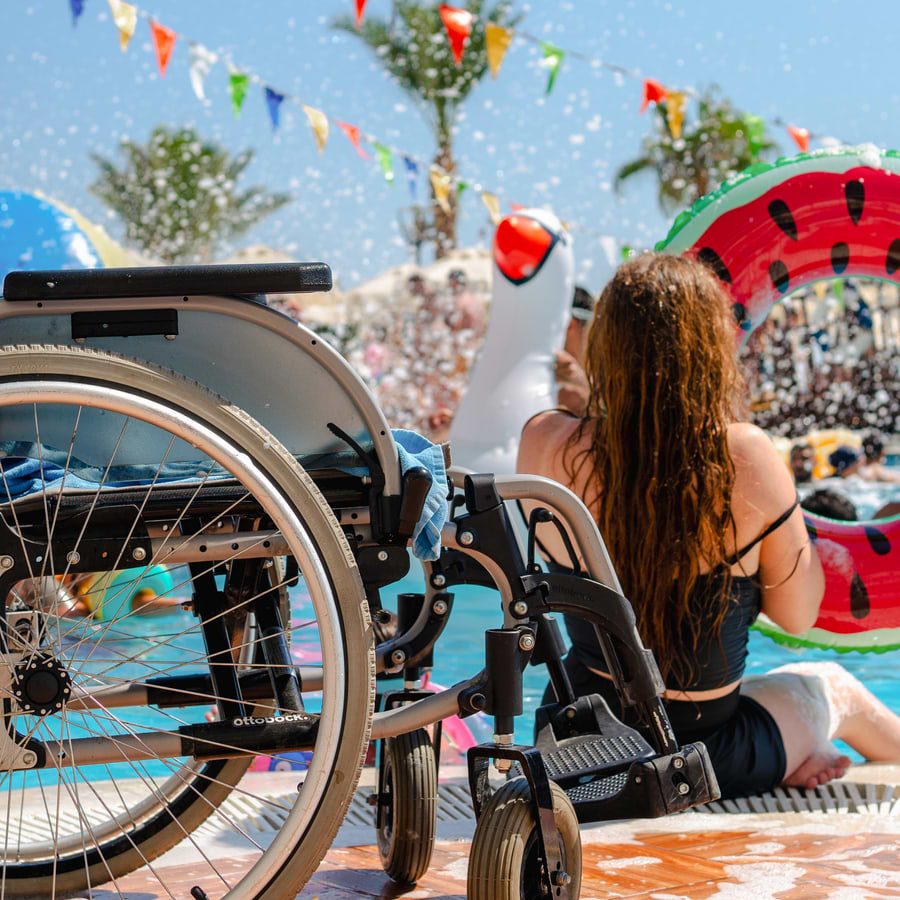 Woman sitting by pool next to wheelchair