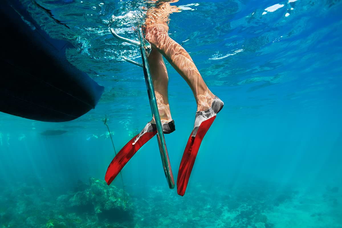 Person going down a ladder on the side of the boat into the ocean to snorkel.