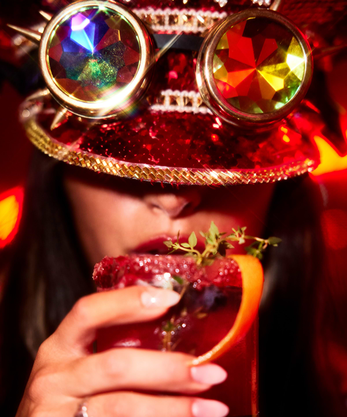 close up shot of woman wearing sparkly red hat drinking out of red cup